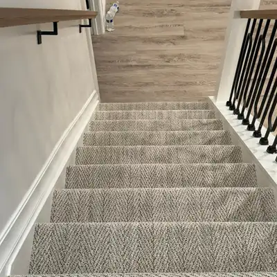 Gray patterned carpet installed on a staircase with iron railing