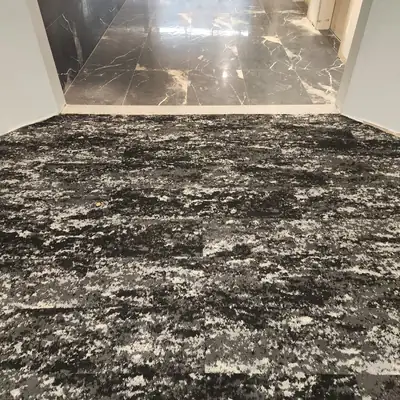 Dark speckled carpet tile meeting a marble-look entry floor in a commercial space