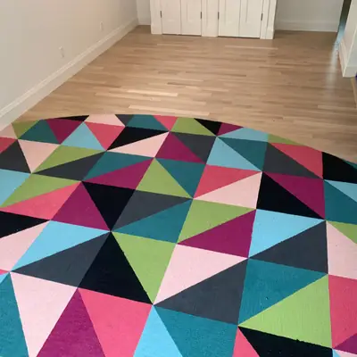 Geometric triangle carpet-tile inlay set into light oak hardwood floor